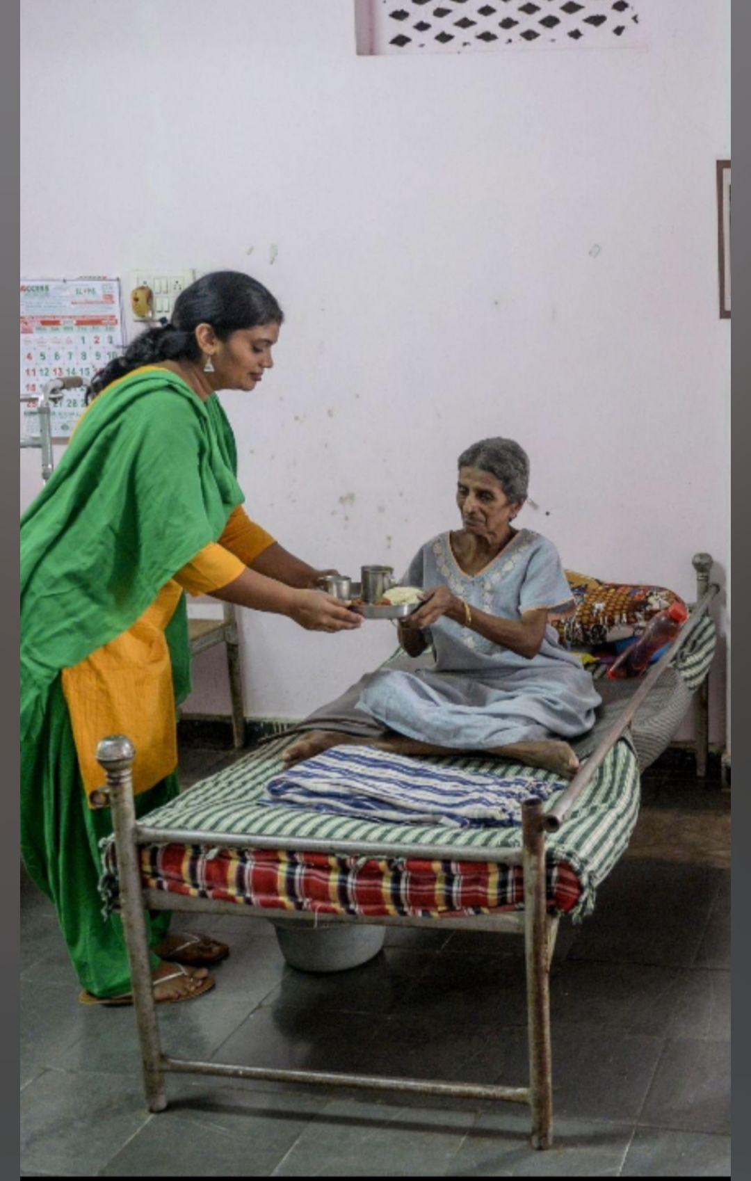 Caregiver serving a meal to an elderly patient at home